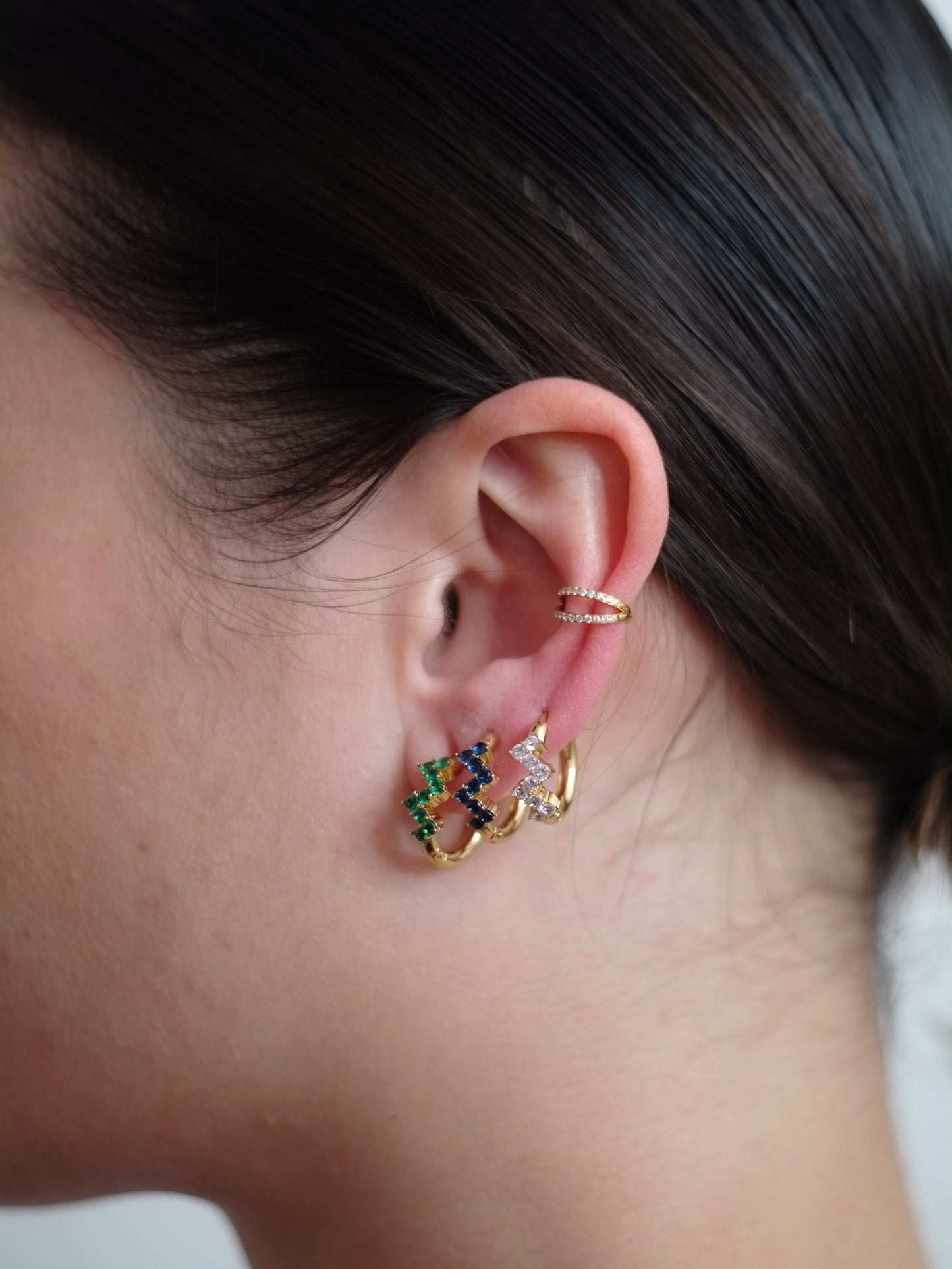 The Lumen 18k Gold Plated Stainless Steel Clustered Crystal Huggie Hoop Earrings in Sapphire Blue Cubic Zirconia.