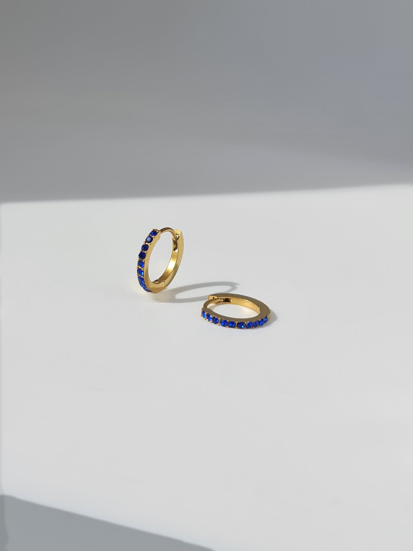 The Maija 'September' Sapphire Birthstone 18k Gold Plated Stainless Steel Crystal Huggie Hoop Earrings.