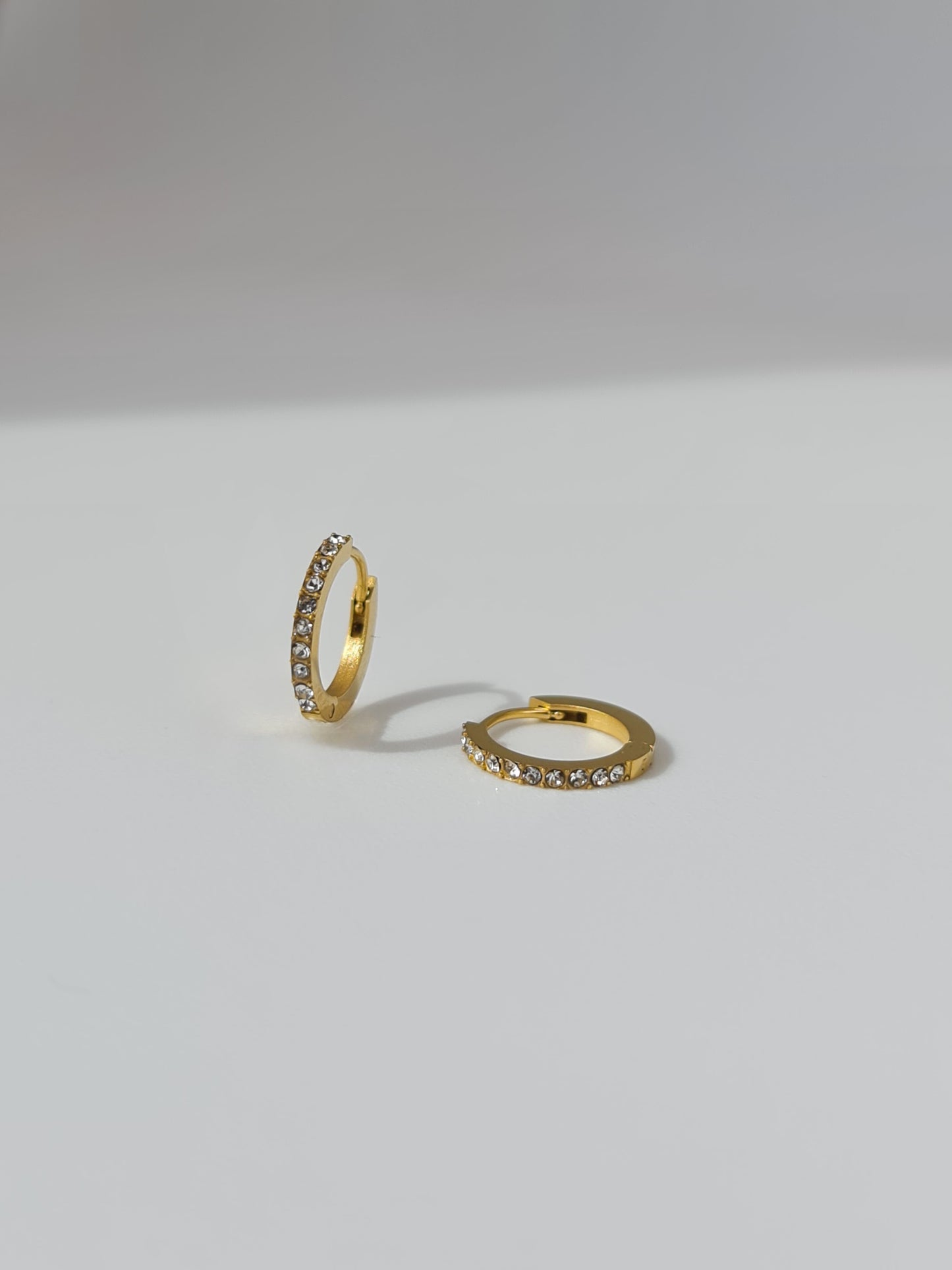 The Maija 'April' Diamond CZ Birthstone 18k Gold Plated Stainless Steel Crystal Huggie Hoop Earrings.