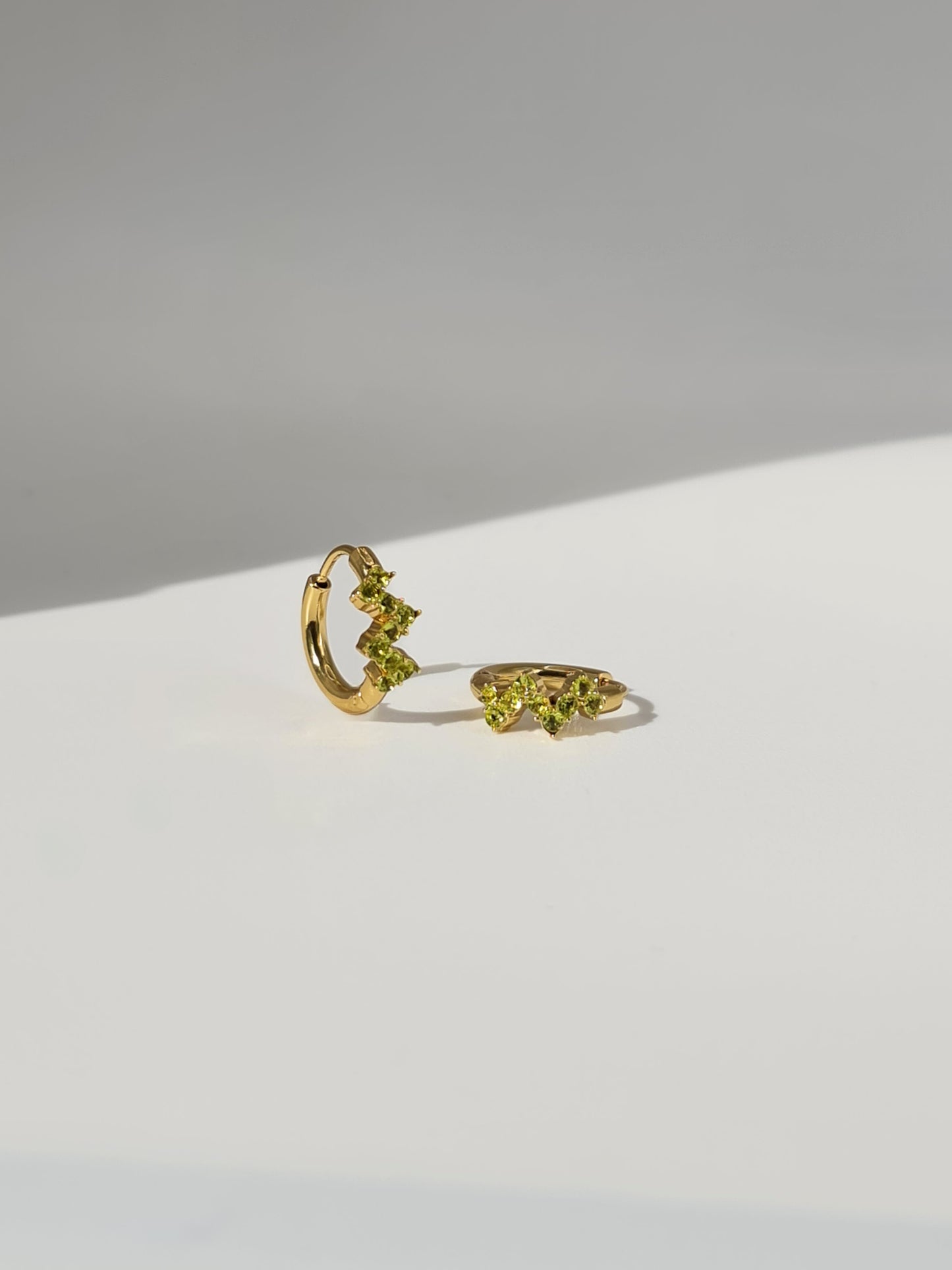 The Lumen 18k Gold Plated Stainless Steel Clustered Crystal Huggie Hoop Earrings in Peridot Green Cubic Zirconia.