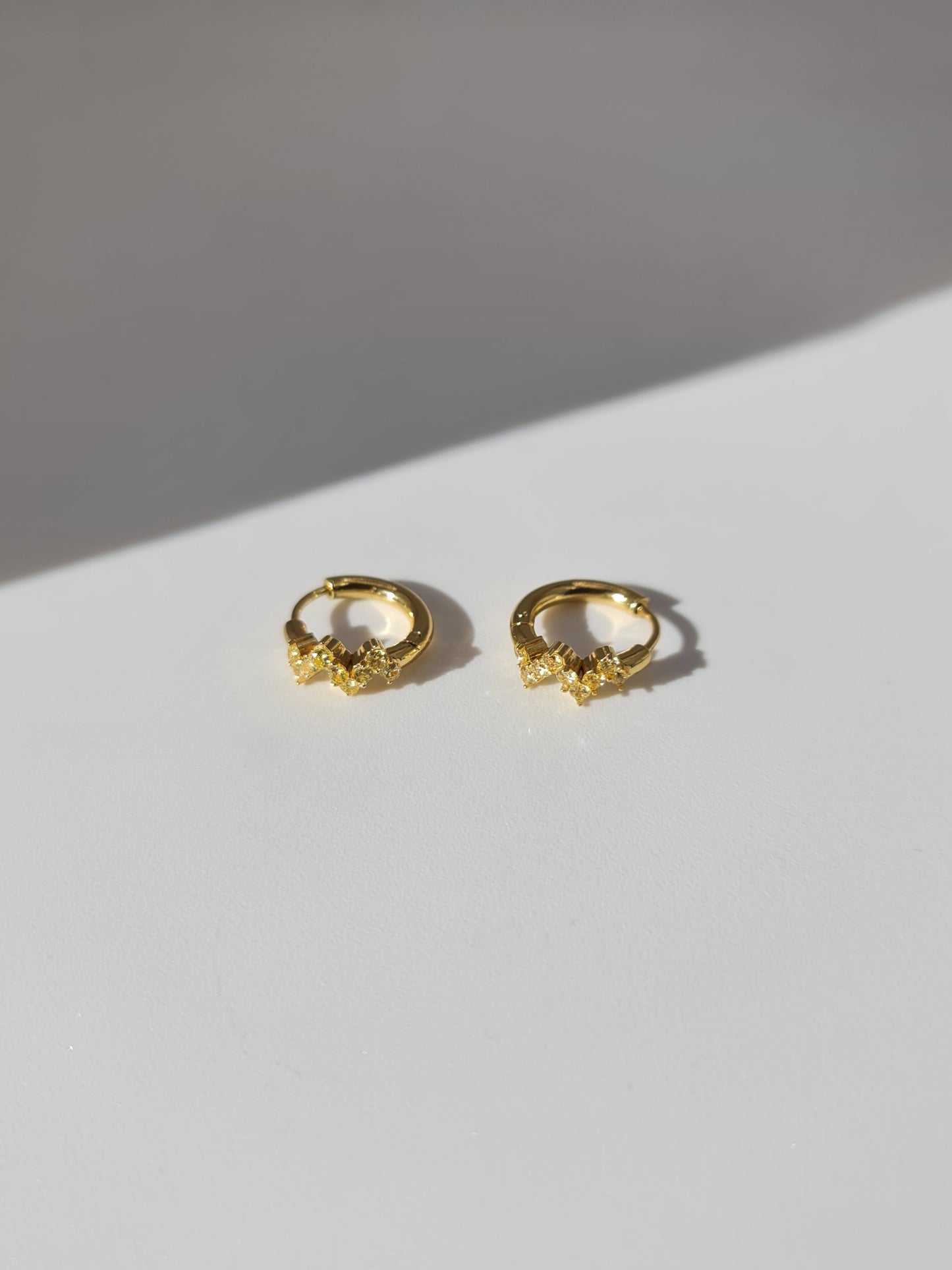 The Lumen 18k Gold Plated Stainless Steel Clustered Crystal Huggie Hoop Earrings in Citrine Yellow Cubic Zirconia.