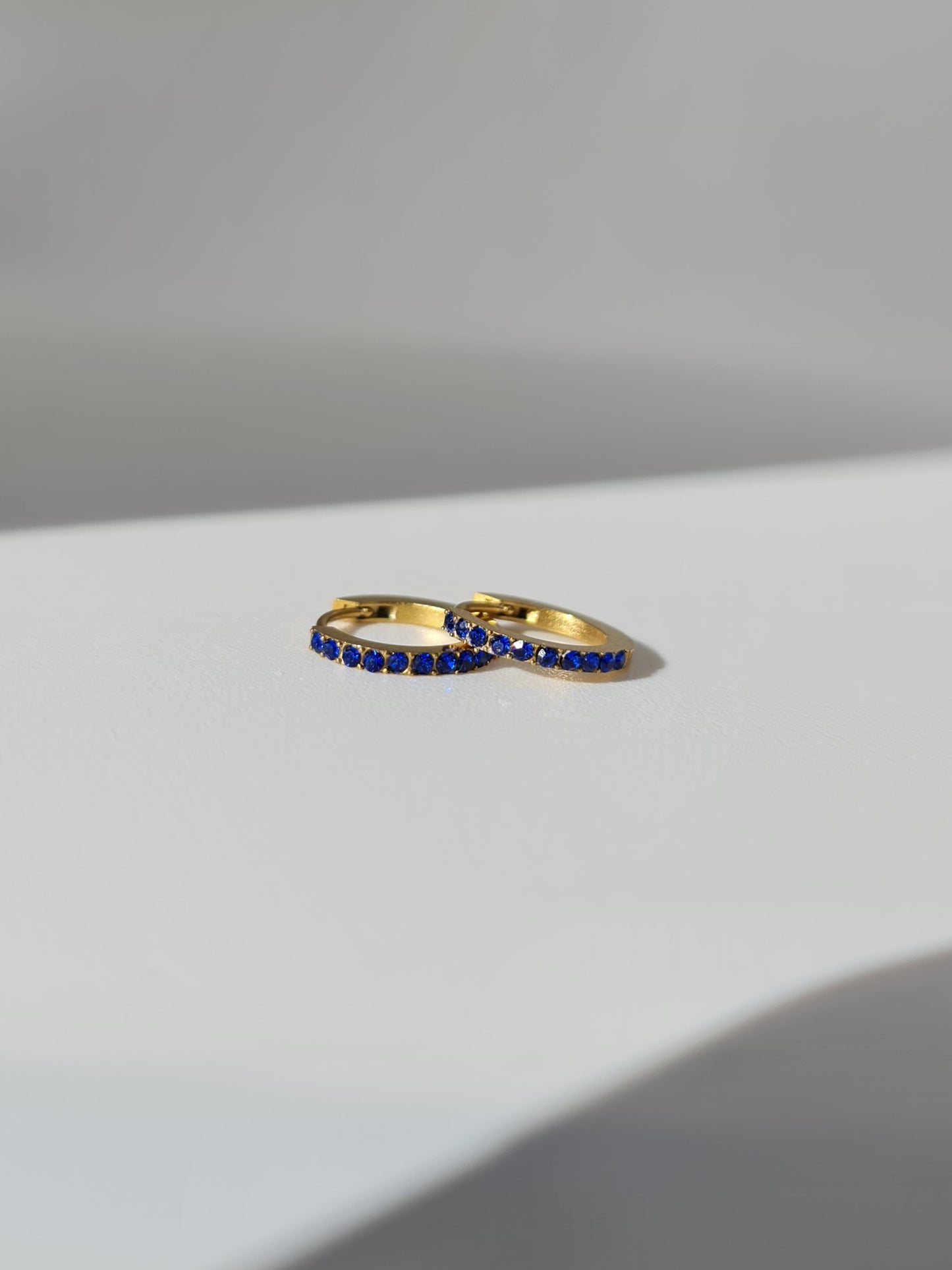 The Maija 'September' Sapphire Birthstone 18k Gold Plated Stainless Steel Crystal Huggie Hoop Earrings.