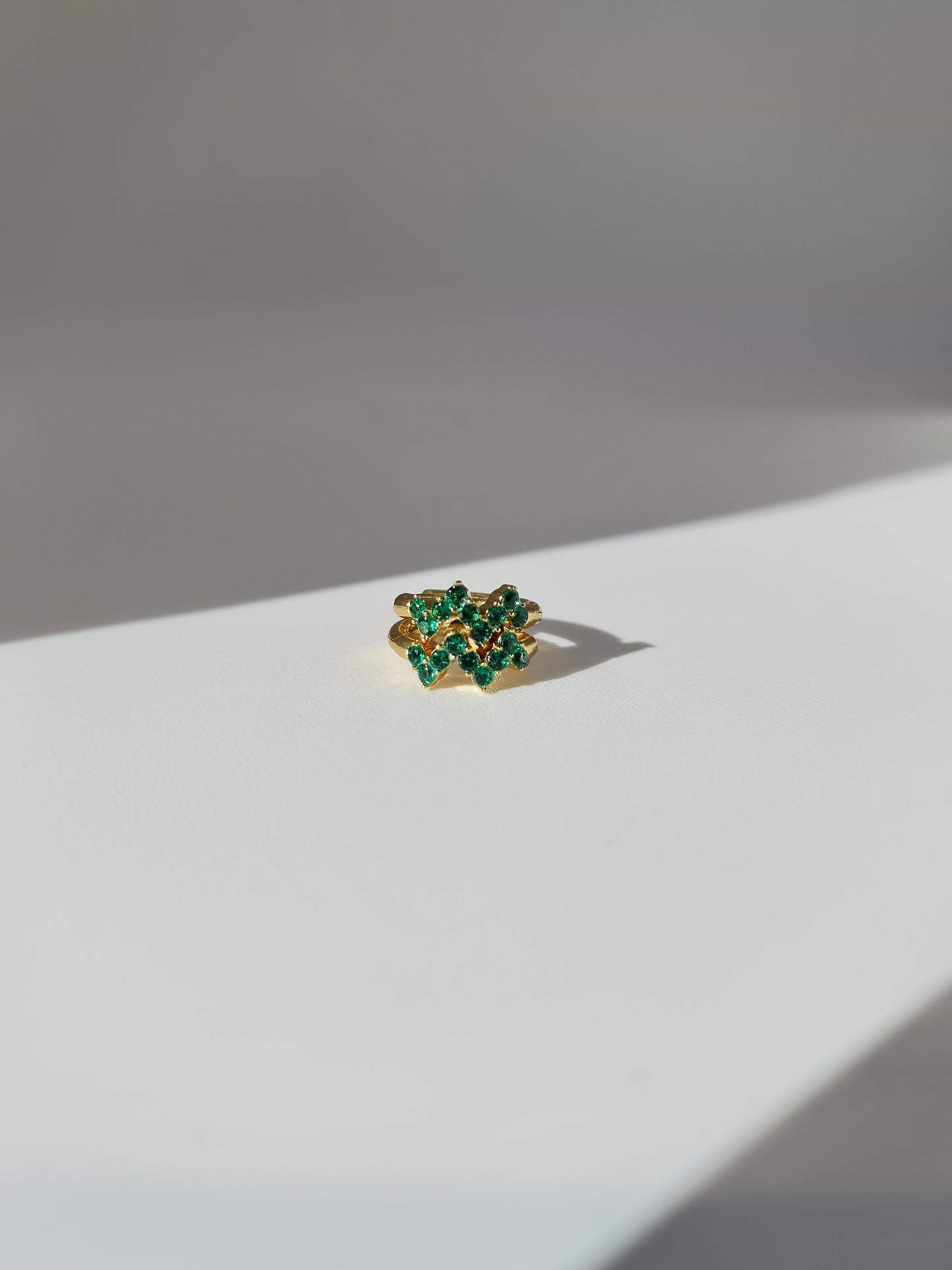The Lumen 18k Gold Plated Stainless Steel Clustered Crystal Huggie Hoop Earrings in Emerald Green Cubic Zirconia.