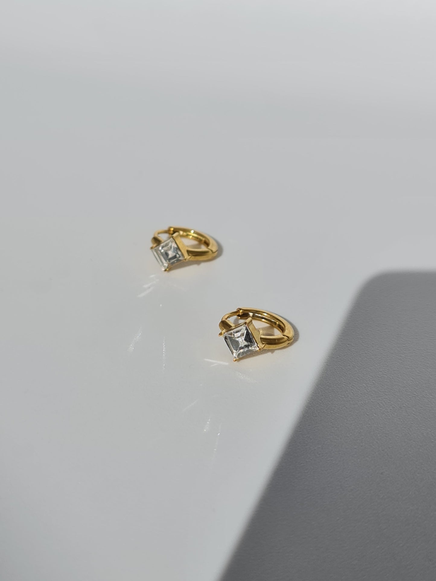 The Billie 18k Gold Plated Stainless Steel Princess Cut Cubic Zirconia Crystal Huggie Hoop Earrings.