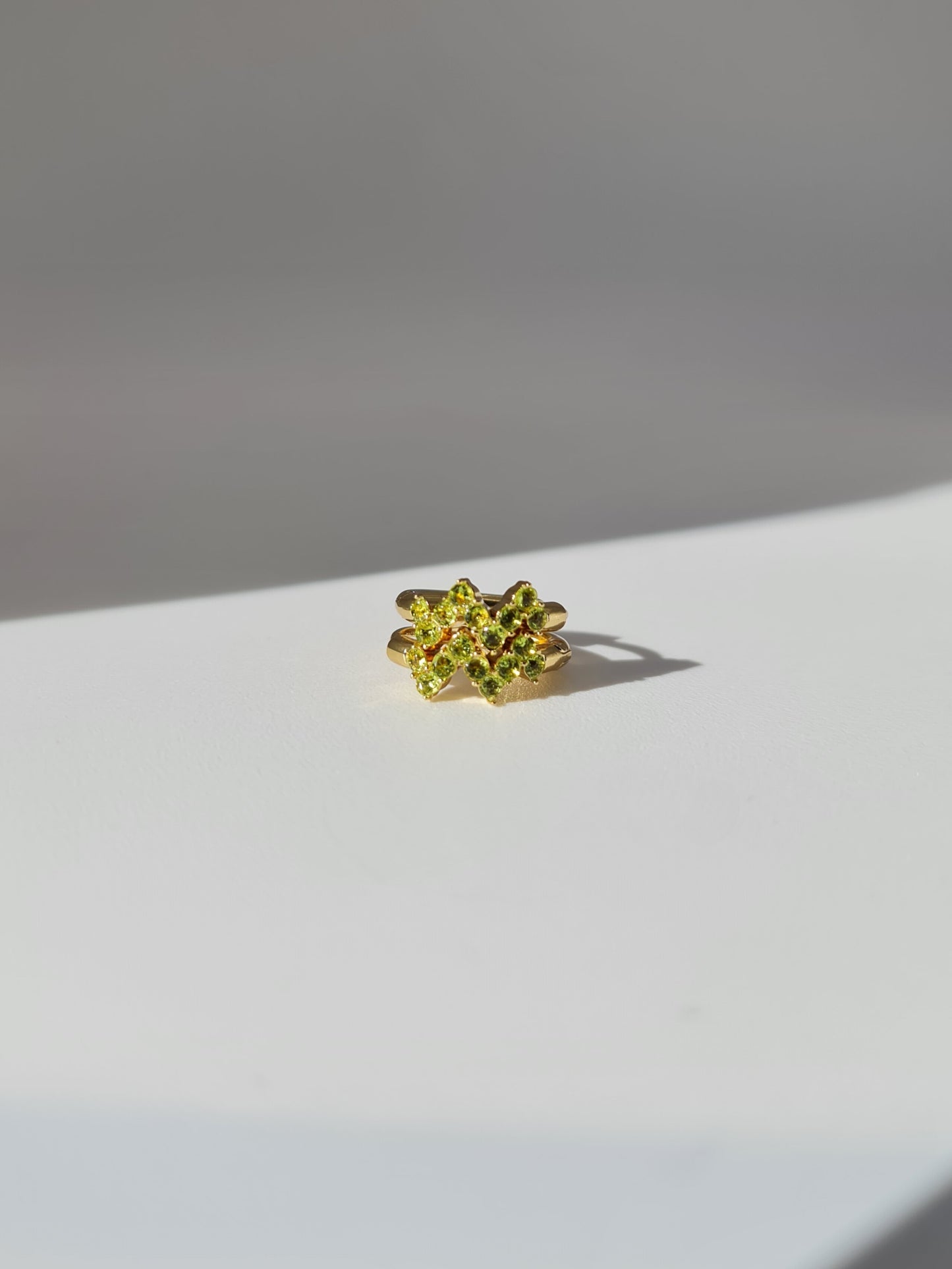 The Lumen 18k Gold Plated Stainless Steel Clustered Crystal Huggie Hoop Earrings in Peridot Green Cubic Zirconia.