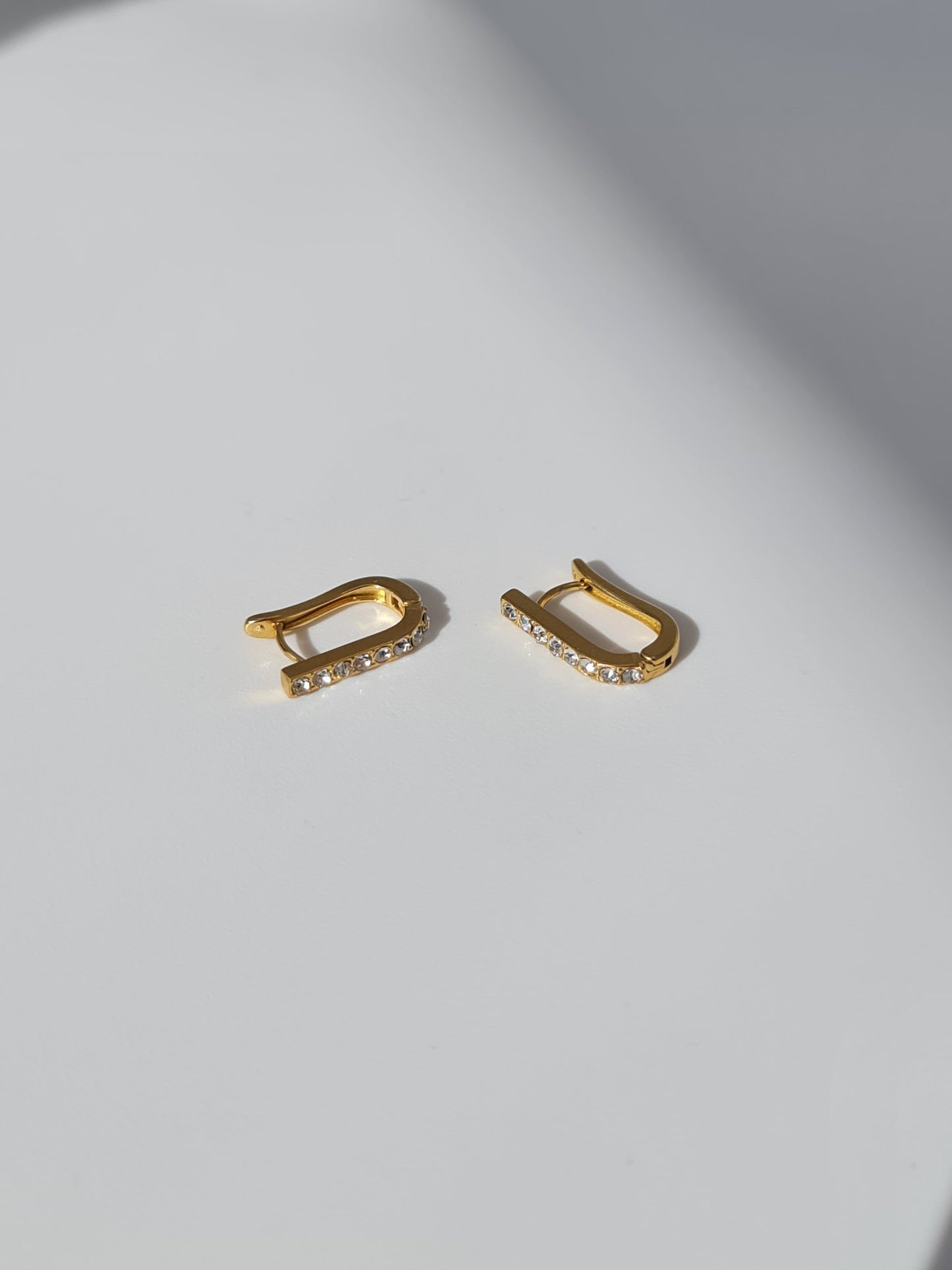 The Bobbie 18k Gold Plated Stainless Steel Cubic Zirconia Pave Crystal Oval Huggie Hoop Earrings.