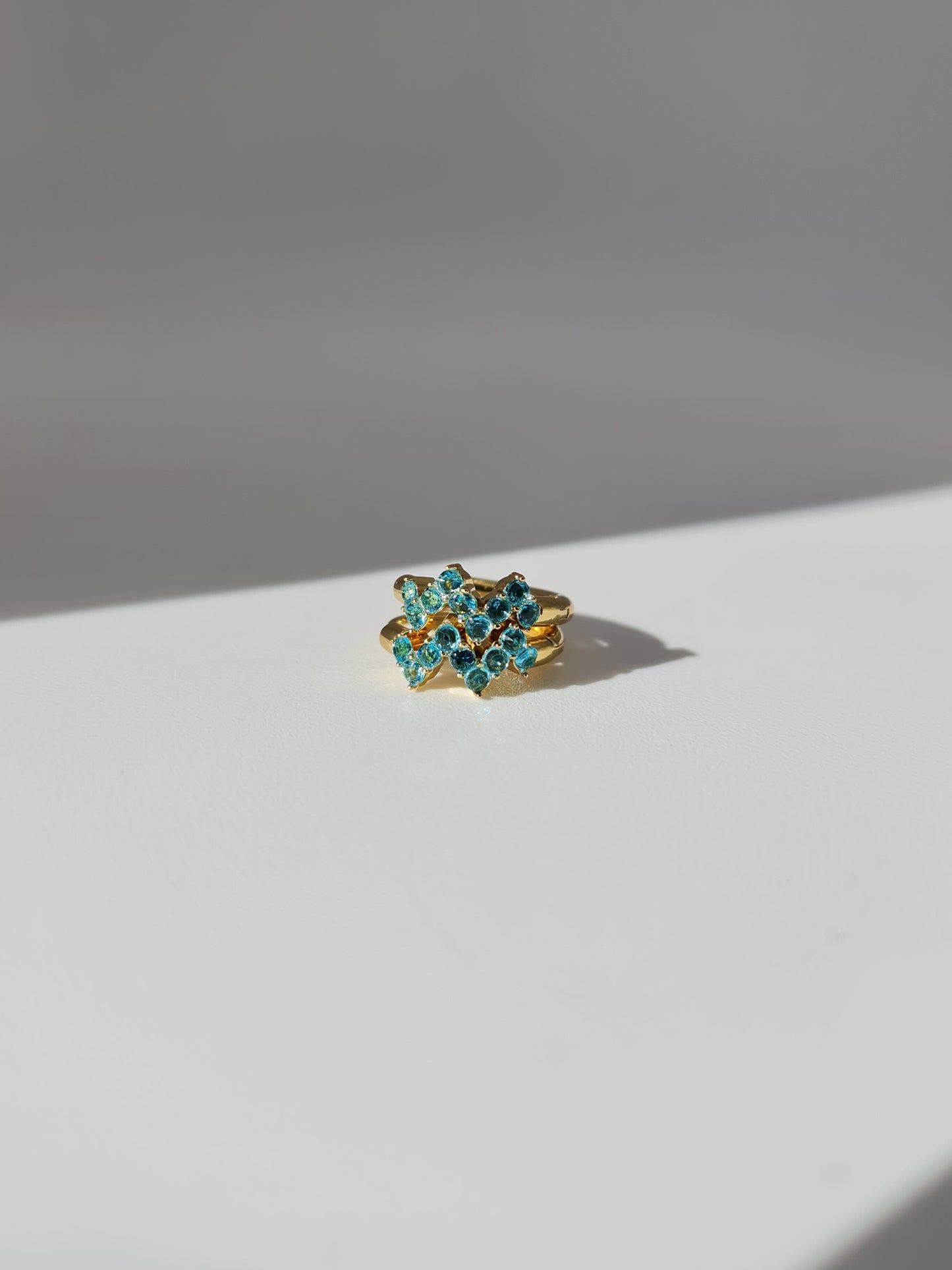 The Lumen 18k Gold Plated Stainless Steel Clustered Crystal Huggie Hoop Earrings in Aquamarine Blue Cubic Zirconia.