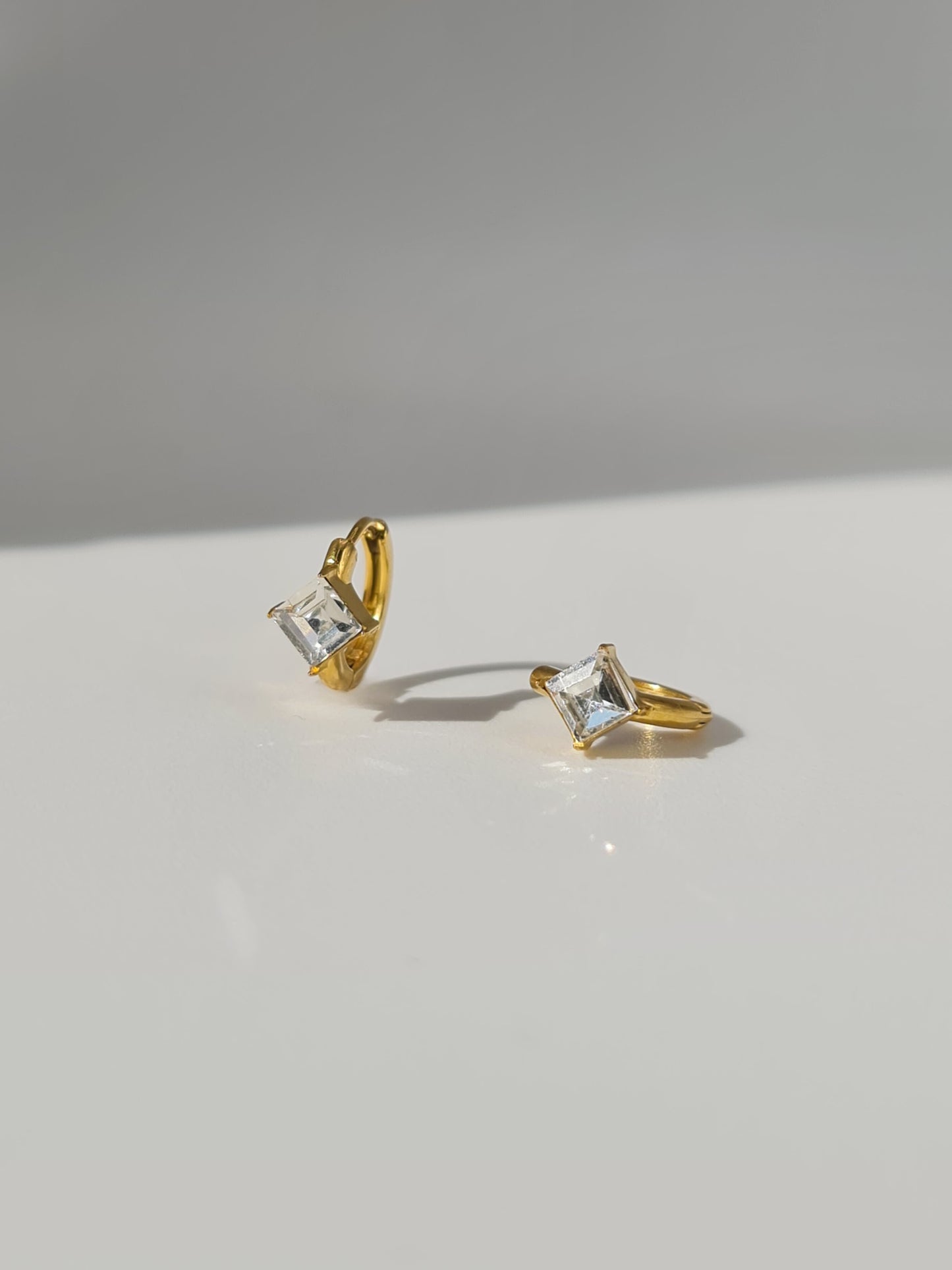 The Billie 18k Gold Plated Stainless Steel Princess Cut Cubic Zirconia Crystal Huggie Hoop Earrings.