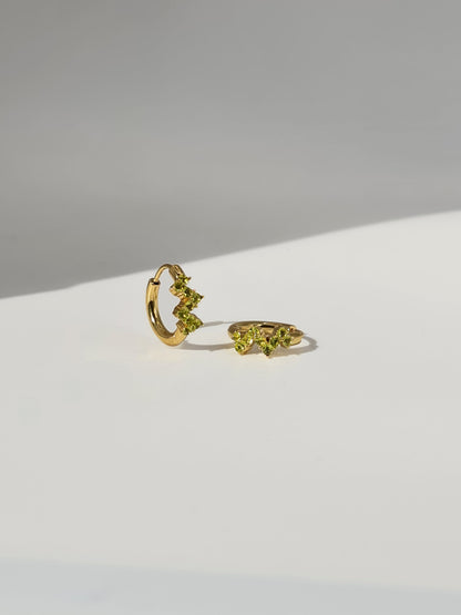 The Lumen 18k Gold Plated Stainless Steel Clustered Crystal Huggie Hoop Earrings in Peridot Green Cubic Zirconia.