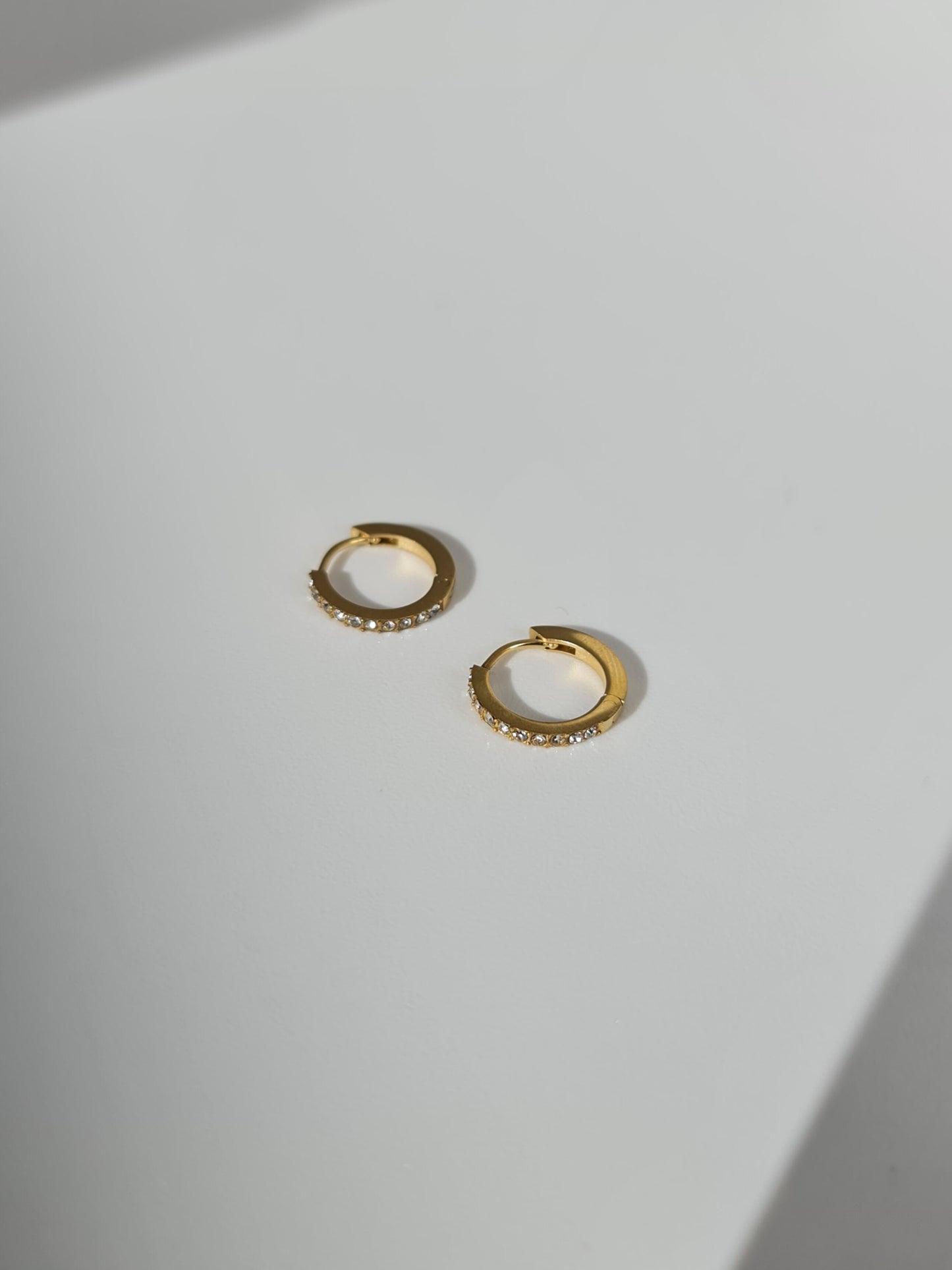 The Maija 'April' Diamond CZ Birthstone 18k Gold Plated Stainless Steel Crystal Huggie Hoop Earrings.
