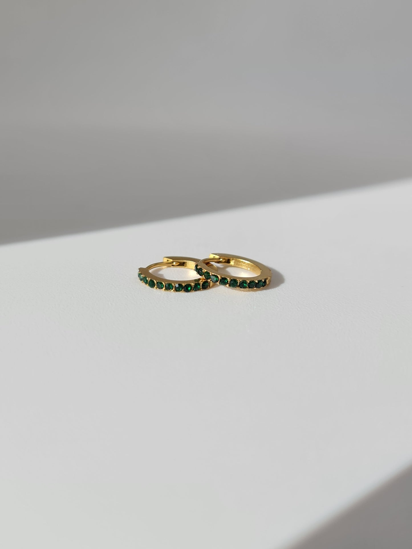 The Maija 'May' Emerald Birthstone 18k Gold Plated Stainless Steel Crystal Huggie Hoop Earrings.
