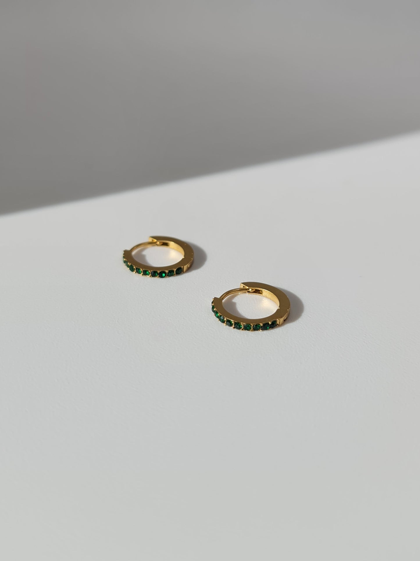 The Maija 'May' Emerald Birthstone 18k Gold Plated Stainless Steel Crystal Huggie Hoop Earrings.