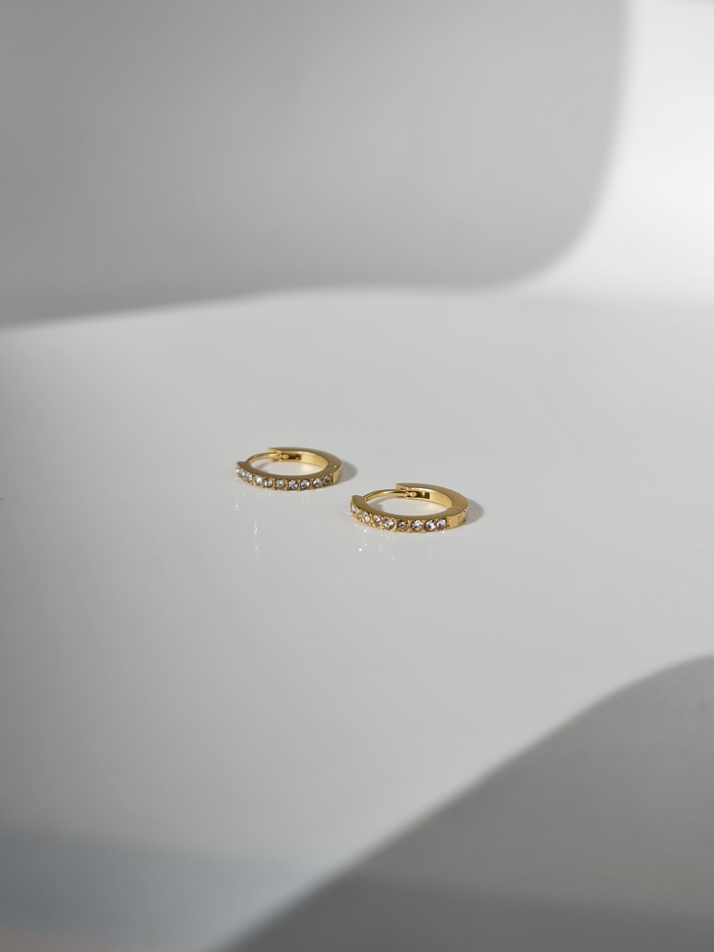 The Maija 'April' Diamond CZ Birthstone 18k Gold Plated Stainless Steel Crystal Huggie Hoop Earrings.