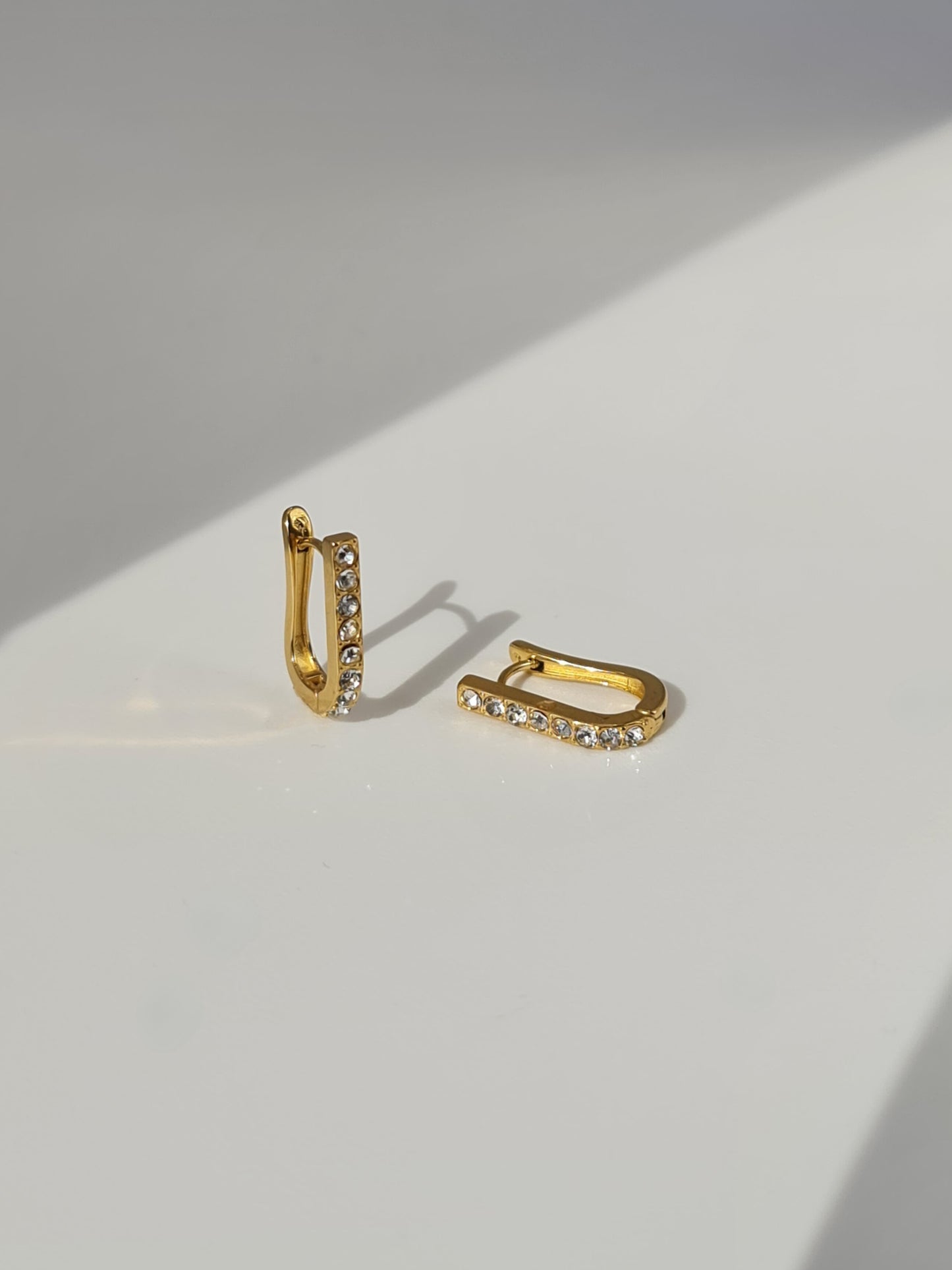 The Bobbie 18k Gold Plated Stainless Steel Cubic Zirconia Pave Crystal Oval Huggie Hoop Earrings.